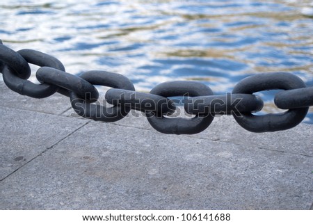 Black chain links closeup before sea embankment