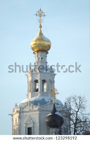 Top of Russian country church with golden cupola over blue sky in winter