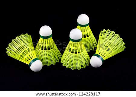 Five yellow badminton shuttlecocks with white cork isolated on black