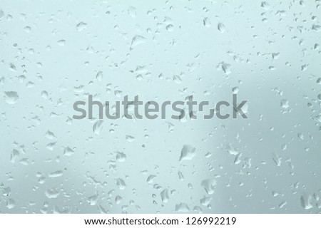 Many cold rain drops on window glass closeup as background