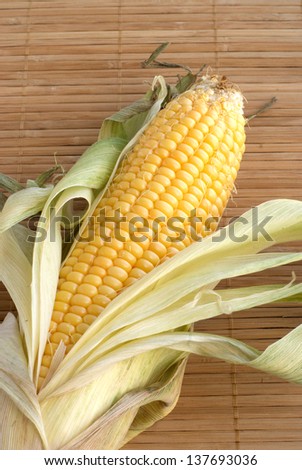 Single ripe corn cob on table over star mat