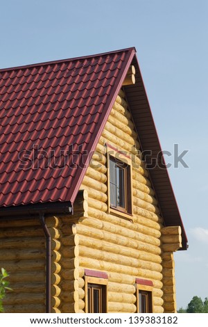 Top of country wooden house with red roof and windows closeup