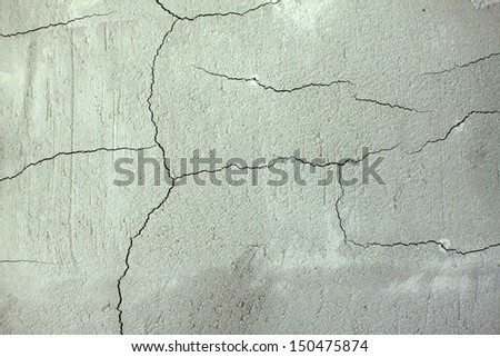 Cracks in gray concrete wall close up as background