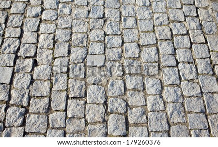 Street paved with gray cobblestones. Close-up view