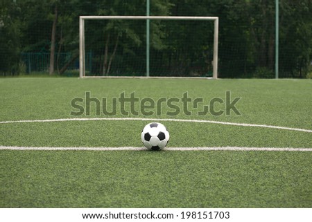Classic white and black ball for playing soccer  on synthetic grass  playground against gate on sport field close-up