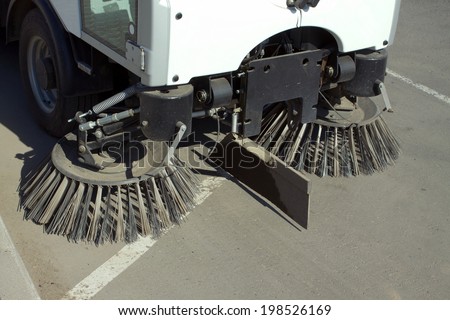 Part of road cleaning machine with round front brushes closeup