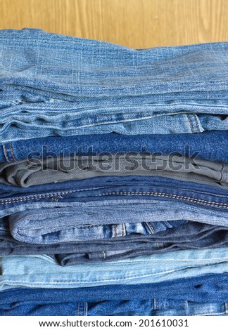 Many colored jeans on on sandy brown background vertical view close-up