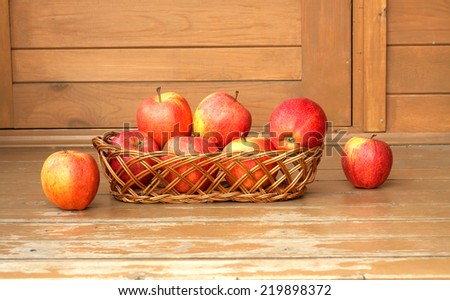 Autumn still life with ripe red apples in wicker basket  on a wooden surface painted brown