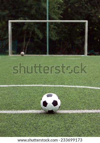 Classic ball for playing soccer in white with black accents on artificial turf against gate, close-up view