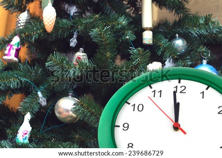 Clock showing almost twelve hours against toys on dressed up on Christmas tree