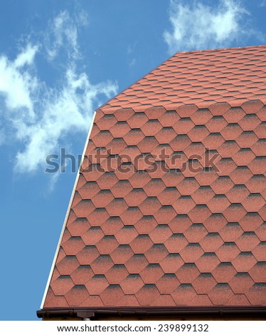 Roof of a country house covered with soft tile closeup against blue sky with light clouds