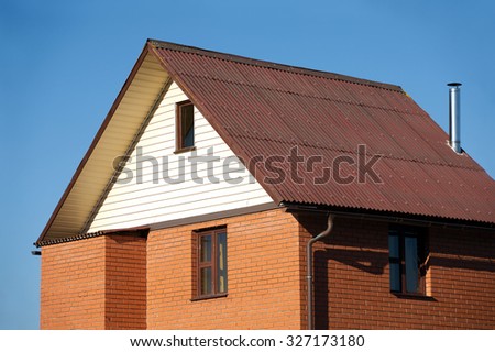 New country house of red brick, brown roof covered and siding on the front and a metal chimney