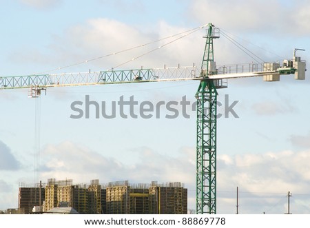 Tower hoisting crane over building construction
