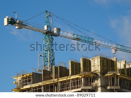 Hoisting tower crane above building house