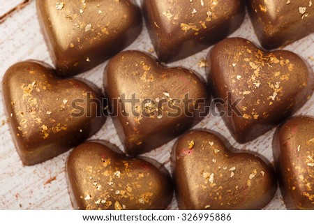 The chocolate candies decorated with edible gold powder on white wooden table