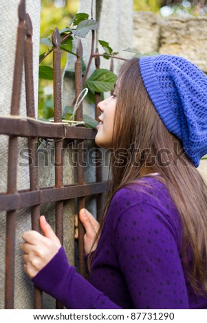 Girl spying through a hole in a fence