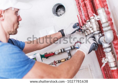Professional Plumber Work. Caucasian Worker Checking on Water Valves.