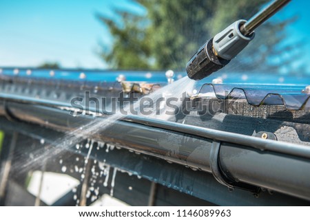 Spring Rain Gutters Cleaning Using Pressure Washer. Closeup Photo.