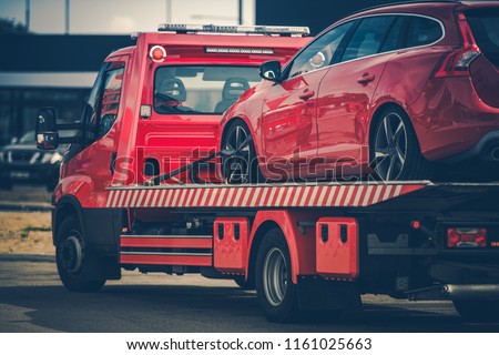 Red Broken Car on a Red Towing Truck. Closeup Photo. Vehicle Mechanical Problem on the Road.