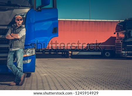 Short Truck Stop Break. Caucasian Semi Trucker in Front of His Modern Truck Tractor.