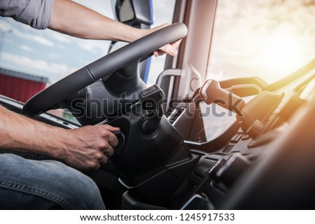 Euro Truck Driving. Modern Semi Truck Cabin Interior. Caucasian Trucker Placing Hand on a Steering Wheel.