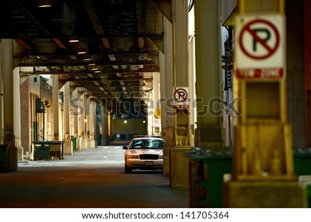 Downtown Chicago Alley Under Train Tracks and Police Cruiser Parked in a Distance. \