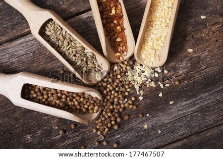 Organic Dry Spices in Wood Scoops on Reclaimed Vintage Wood Table Closeup. Crushed Red Pepper, Coriander, Fennel and Garlic.