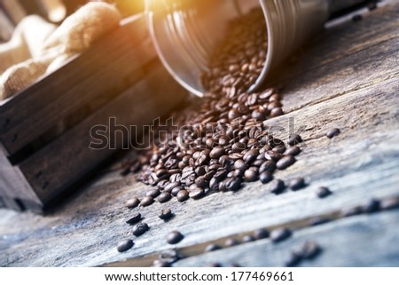 Scattered Coffee Beans From Silver Bucket on Reclaimed Wood.