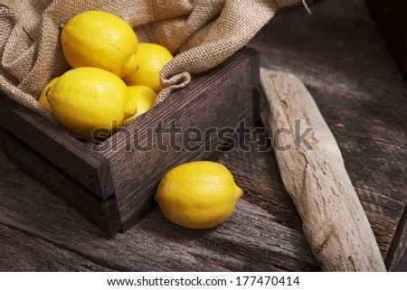 Lemons in Small Wooden Crate on Aged Wood Table.