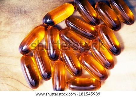 Fish Oil Capsules on Wooden Table Closeup.