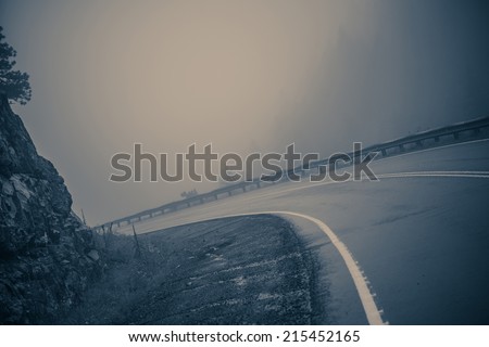 Foggy Curved Road. Dangerous Mountain Road. Bluish Color Grading.