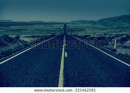 Down the Road. Straight Desert Highway in Bluish Color Grading. Straight Road to Nowhere.