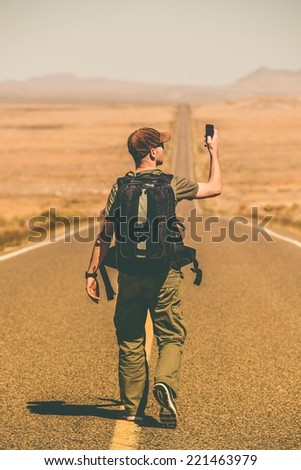 Mobile Phone Signal Search. Traveling Man with Backpack Looking for Cell Phone Reception in the Middle of Nowhere.