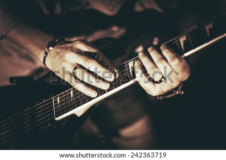 Rockman Playing Electric Guitar Closeup Photography. Hands on Guitar. Elegant Browny Color Grading.