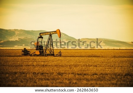 Aged Oil Pump on Colorado Prairie with Mountain Hills in the Background. Oil Industry Theme.