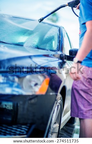 Self Service Car Wash. Young Men Cleaning His Car Using High Pressure Water.