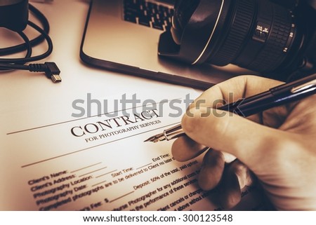 Photography Services Contract Preparing by Professional Photographer on His Work Desk.
