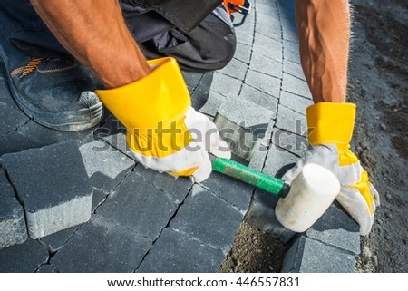 Cobble Brick Paving Works. Men Paving Garden Path using Bricks Closeup Photo.