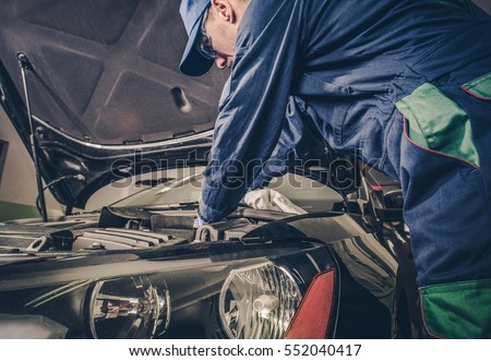 Auto Service Business Concept. Pro Car Mechanic Taking Care of Vehicle. Checking Under the Car Hood.