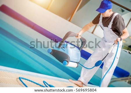 Swimming Pools Technician with Pool Cleaning Robot Preparing For Work. Caucasian Technician Cleaning Professional.