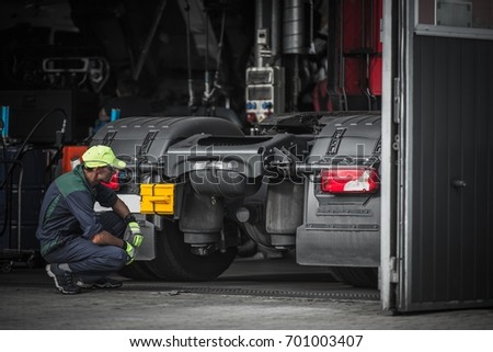 Truck Service Technician Job. Caucasian Truck Mechanic Checking on Semi Truck Tractor.