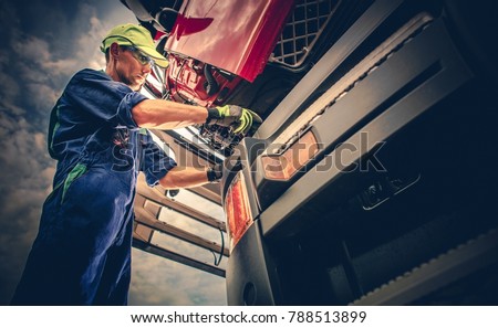 Semi Truck Maintenance. Caucasian Truck Service Worker in His 30s Performing Scheduled Recall Maintenance.