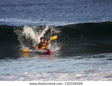 Kayak surfer escaping from big wave on rough sea in Black Cove, Nova Scotia coast, Canada