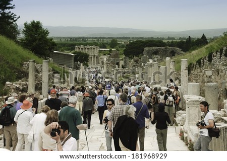 EPHESUS, TURKEY - MAY 8, 2007 : illustrative image of tourists on the ancient marble paved street surrounding by pillars with scenic view of Ephesus site, Turkey