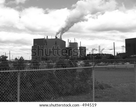 Industrial pollution chimney in urban city near St Lawrence river, Quebec, Canada   - black and white picture grainy in purpose