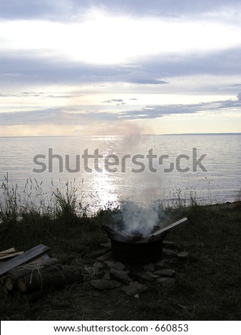 Smoking camping fire in a big iron pot  on coastline of St Lawrence river, Quebec, Canada
