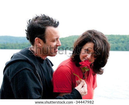 closeup portrait of romantic couple portrait with man giving a rose to her girlfriend