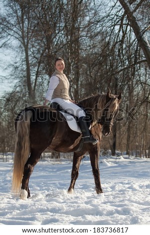 Young woman sits on horseback in spring forest