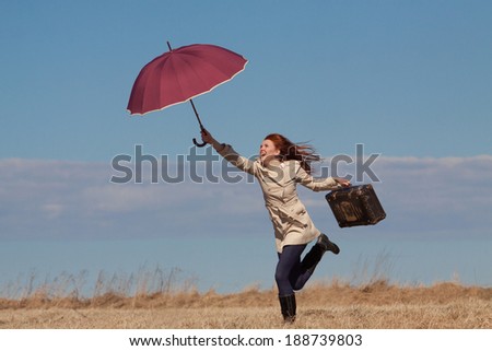 Red haired girl with vintage bag and umbrella