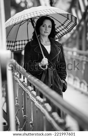 Young woman with umbrella on the bridge. Black and white photo.